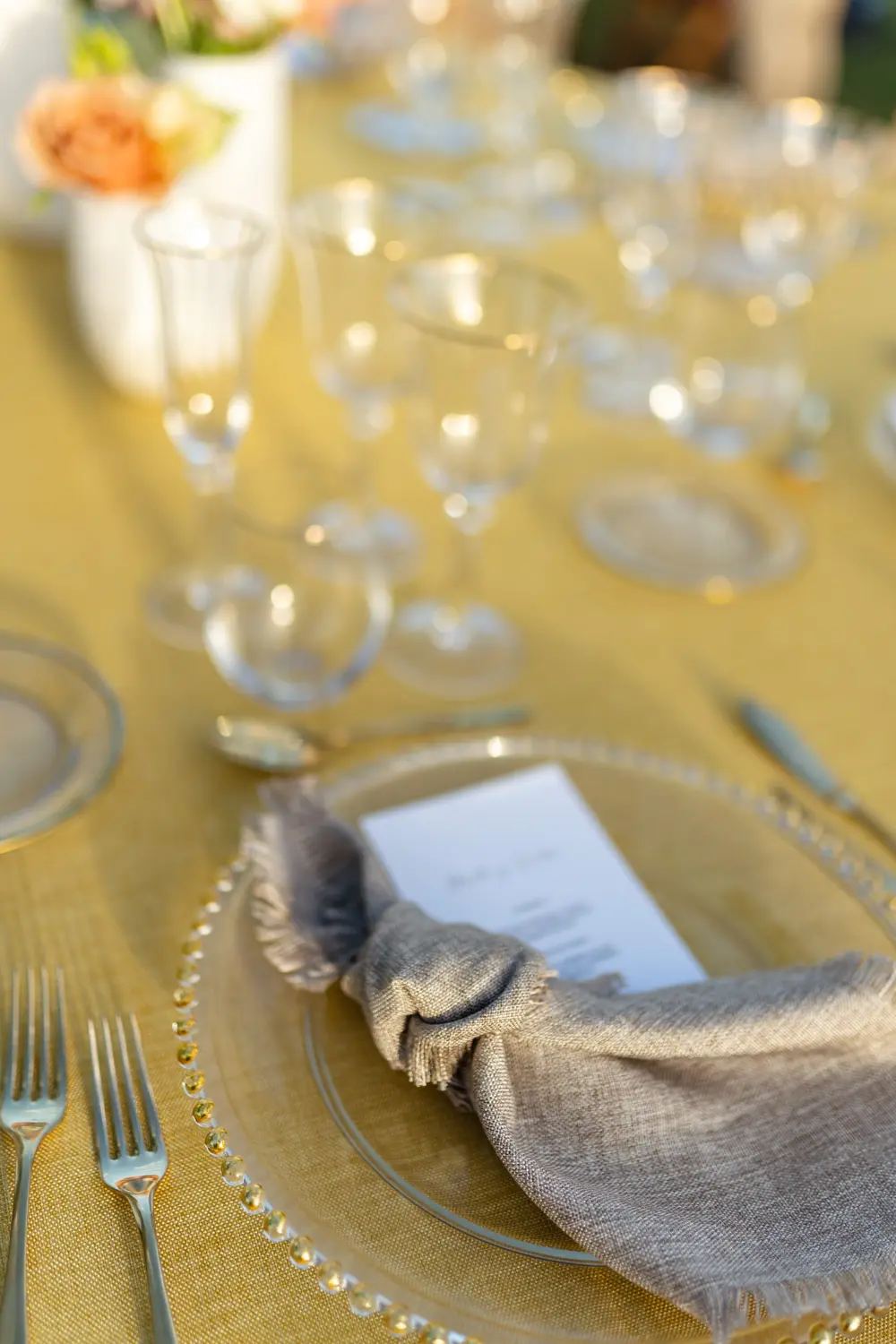 Detalle de cristalería de filo dorado en mesa mostaza