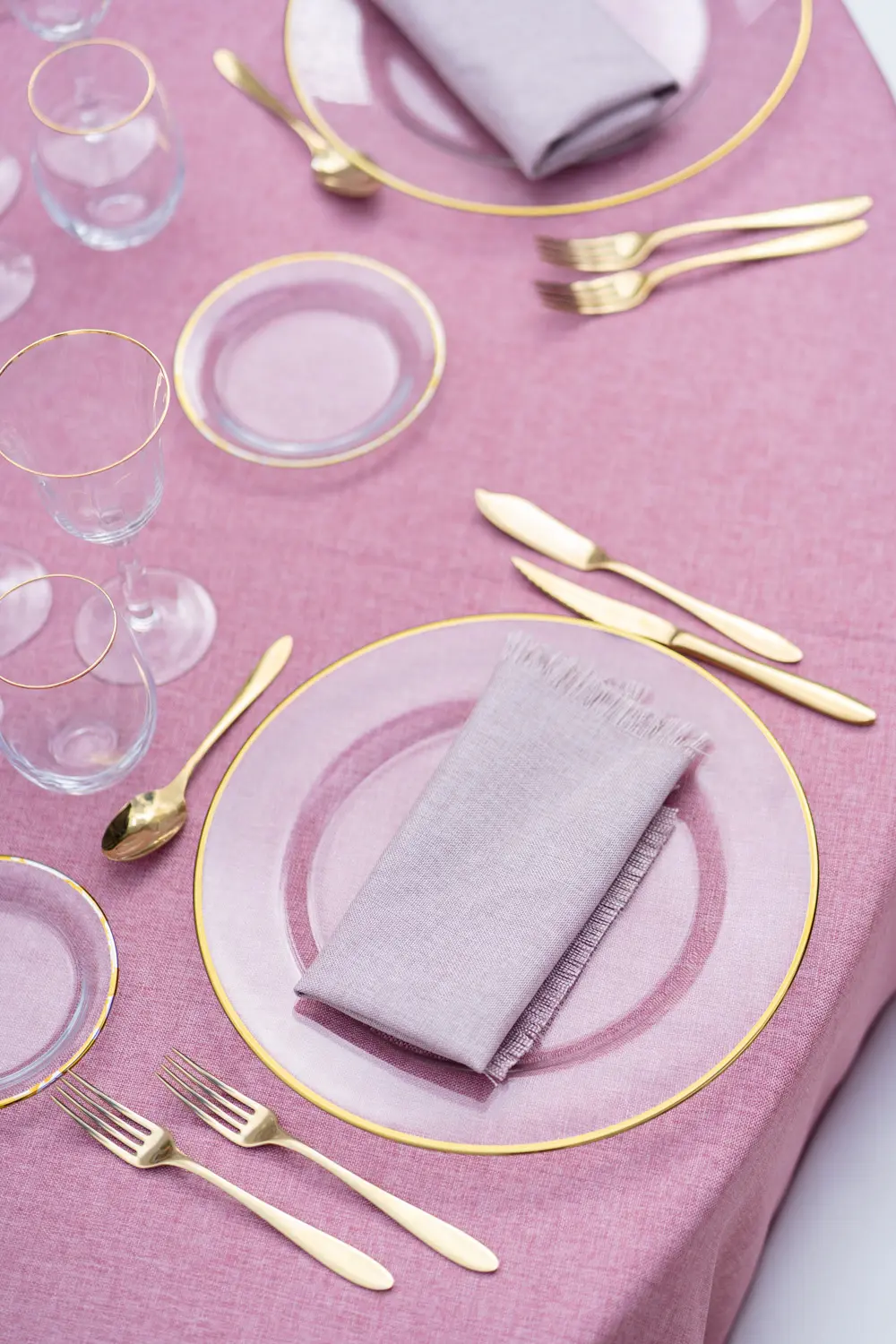 Cristalería de filo dorado en mesa rosa